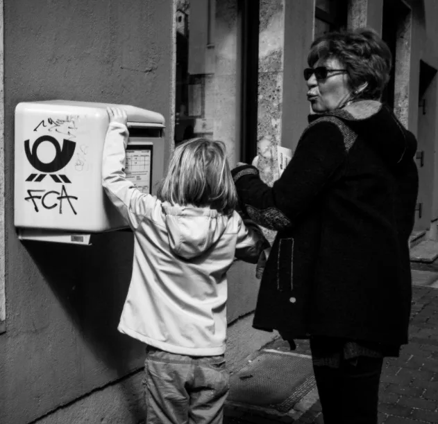 Young child and adult mailing a postcard